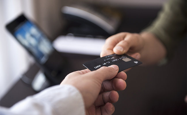 person handing a debit card to another person